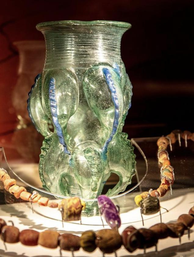 A glass vase filled with colorful beads and decorative items, elegantly displayed on a surface.