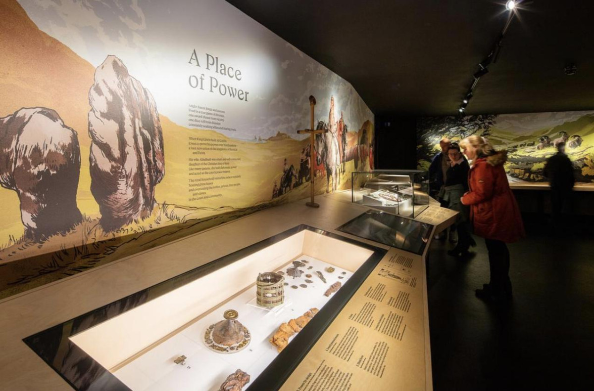 Visitors observing a display of historical artifacts in a museum setting, engaged in learning and exploration.